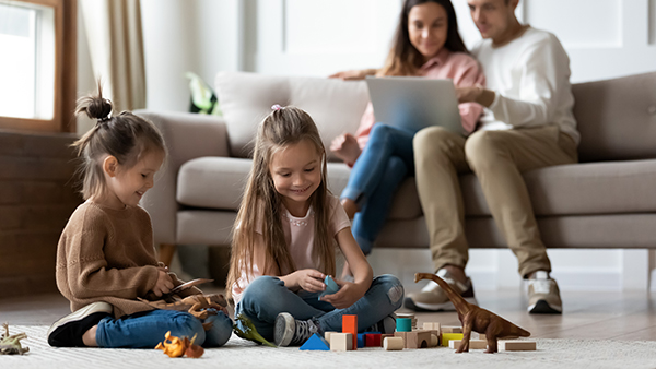 couple looking at a laptop while kids play on the floor