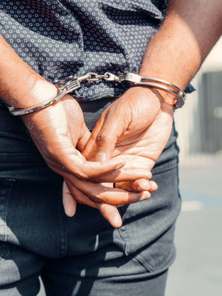 man arrested with his arms behind him in handcuffs