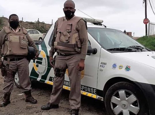 Two armed security guards next to the vehicle