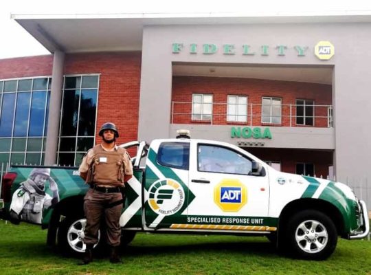 Armed guard next to security vehicle in front of building