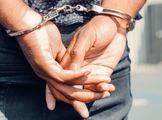 man arrested with his arms behind him in handcuffs
